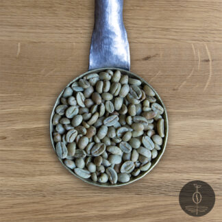 Close-up shot of Ethiopia Sidama green (raw) coffee beans in a handmade scoop with a wooden cutting board background.