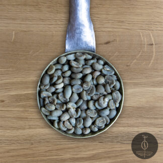 Close-up shot of Sumatra Gayo Mountain green (raw) coffee beans in a handmade scoop with a wooden cutting board background.