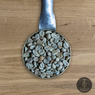 Close-up shot of Honduras Marcala Bird Friendly green (raw) coffee beans in a handmade scoop with a wooden cutting board background.