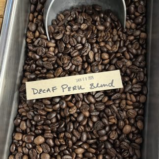 A close-up view of the Decaf Peru Cajamarca roasted coffee beans showing their shape, size, and blend of lighter and darker roasted beans.